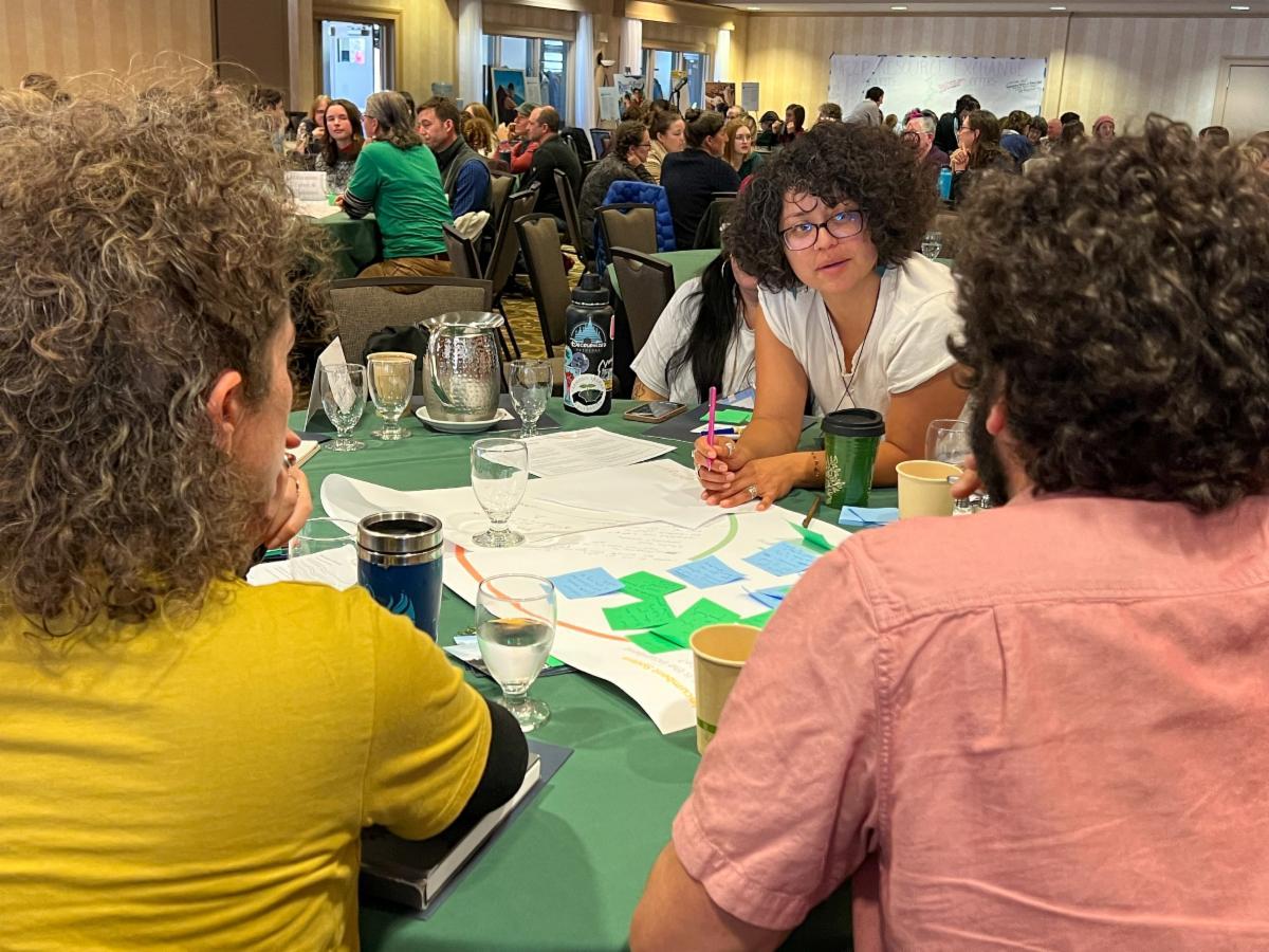 3 people working around a table at the 2023 Farm to Plate Gathering