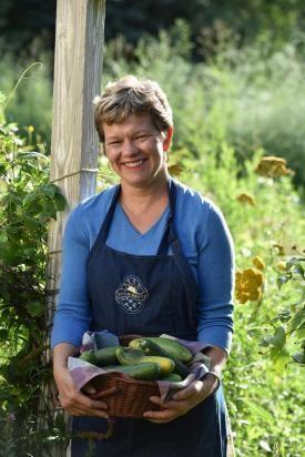 Lisa Kivirist, sustainable agriculture advocate, stands outside with a basket of cucumbers