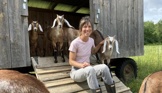 woman farmer with goats next to mobile farm shed